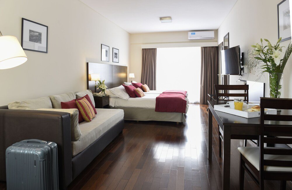 Quarto de hotel com sofá, cama e área de jantar