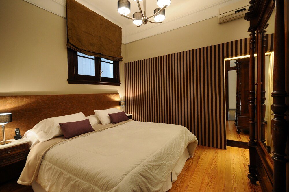 Neatly made bed with white and purple linens