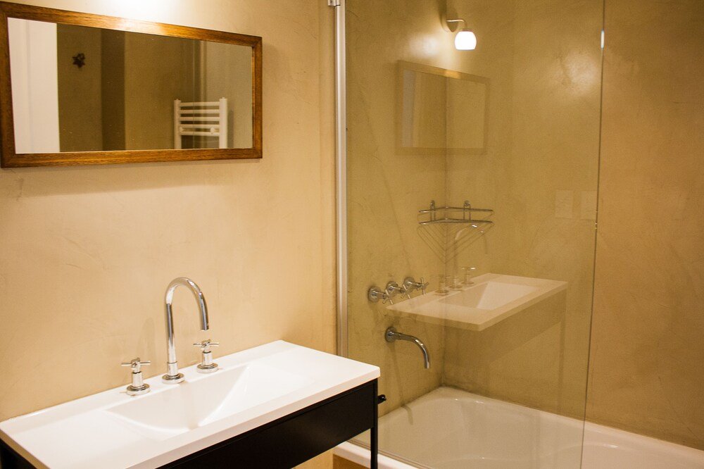 Baño con lavabo blanco y ducha de vidrio