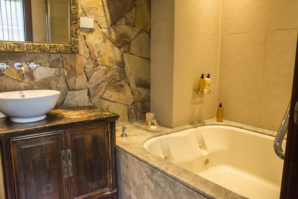 Salle de bain avec mur en pierre et lavabo blanc